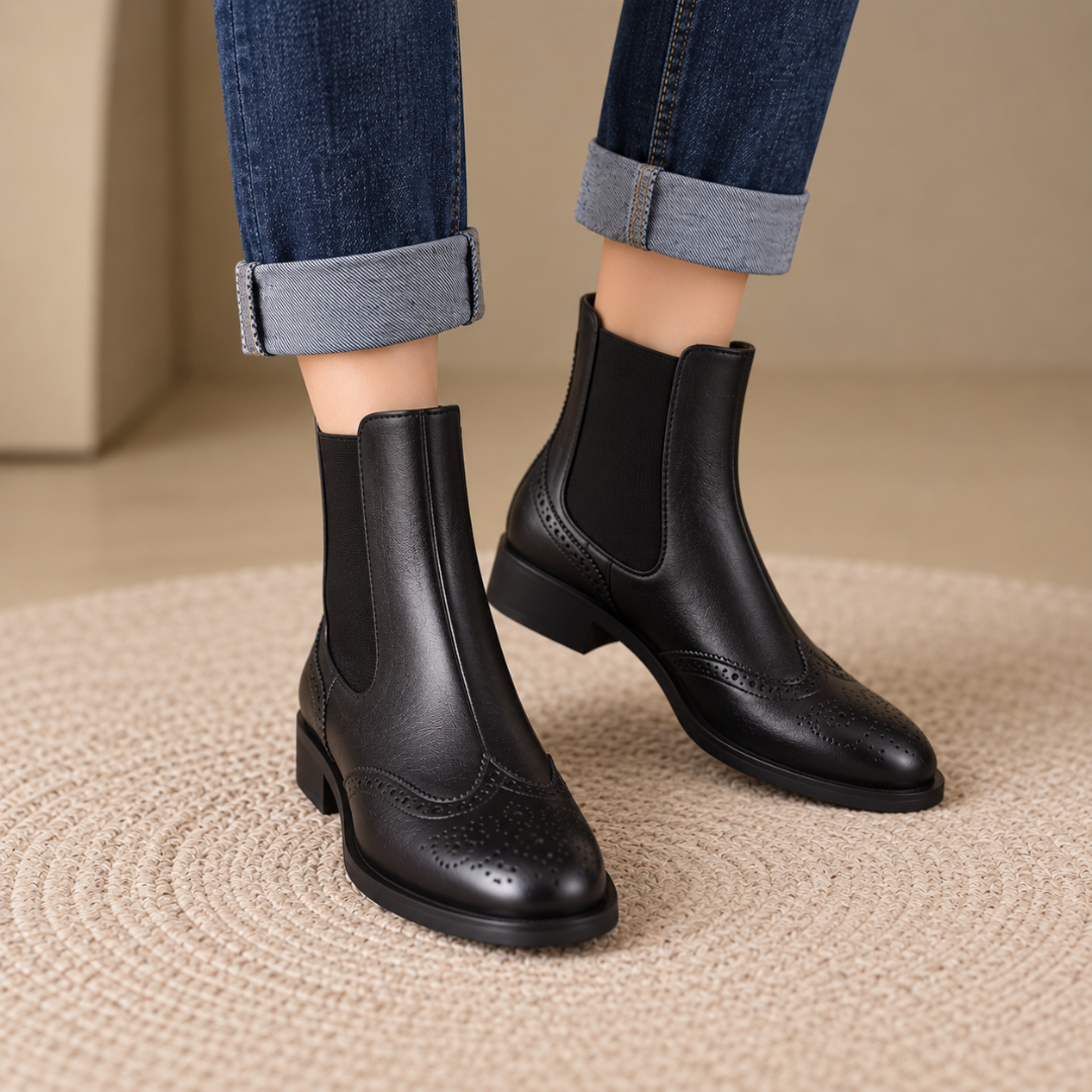 Bottines Chelsea noires à perforations brogue portées avec un pantalon bleu à revers