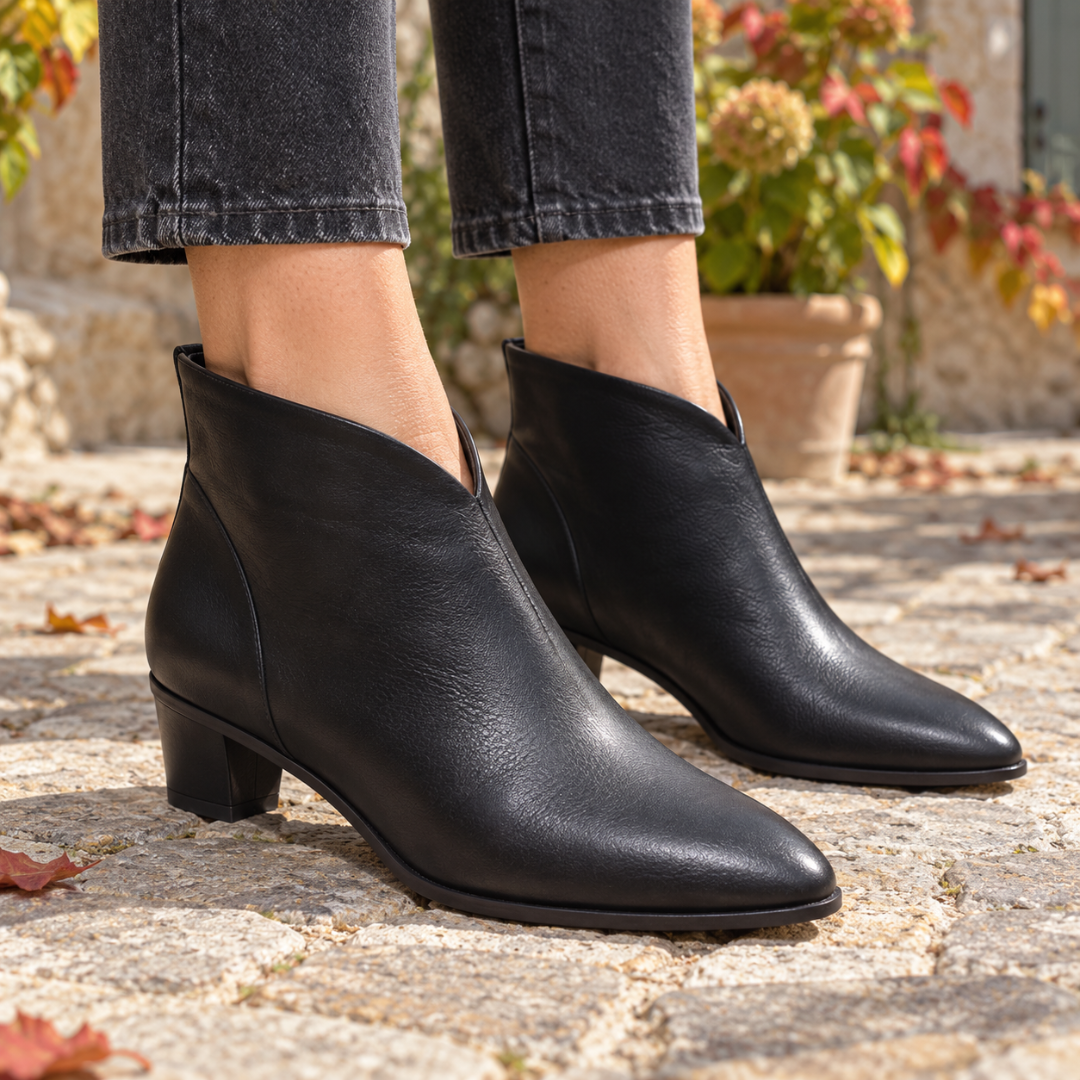 Bottines femme noires à décolleté en V et bout effilé sur dalles de pierre