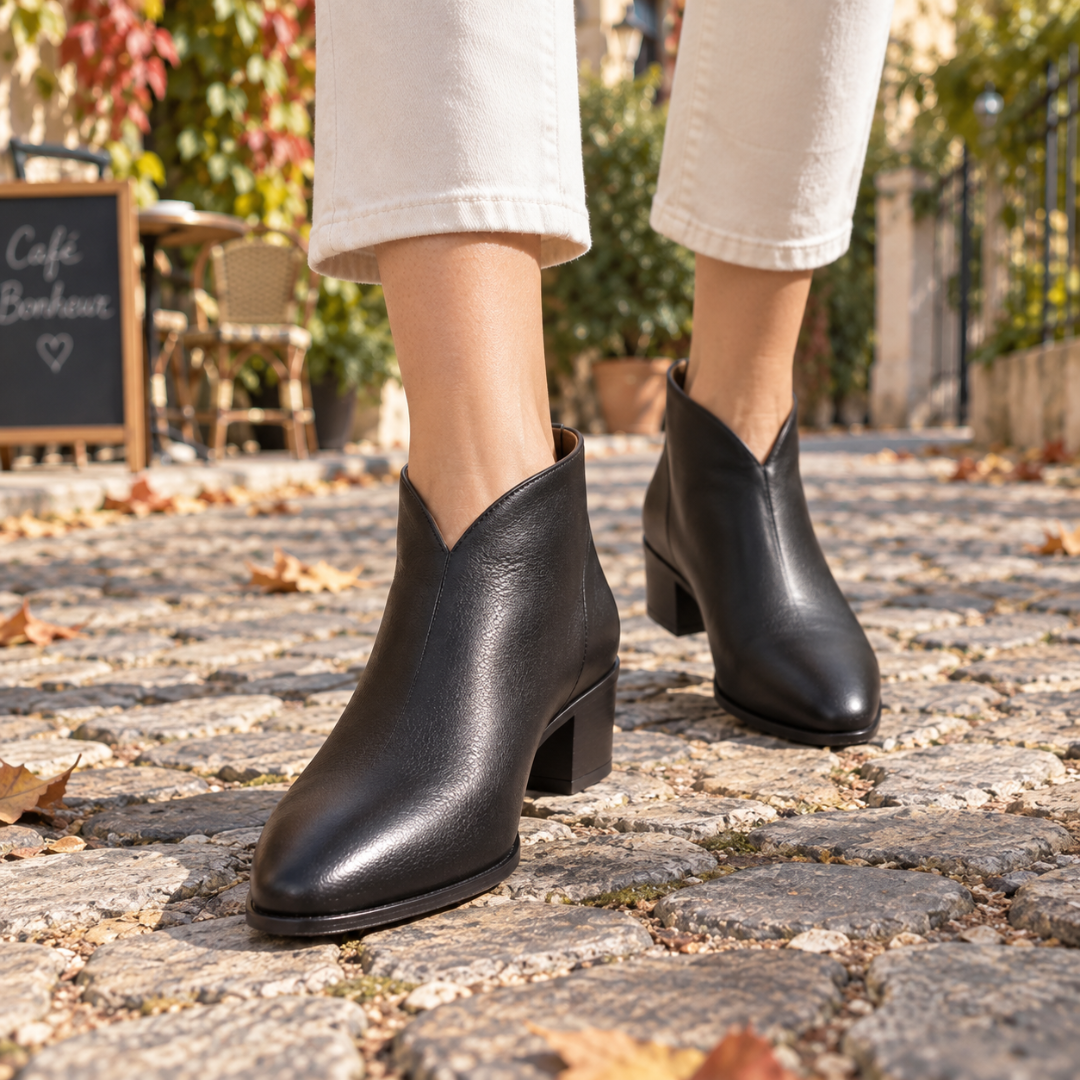 Gros plan sur des bottines noires échancrées en V marchant sur des pavés