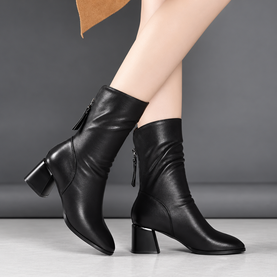 Bottines noires à talon carré portées, jambe tendue, tige souple plissée à la cheville