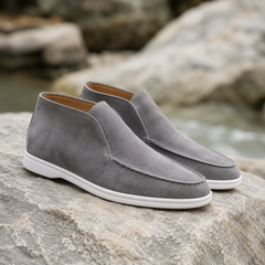 Bottines gris clair à enfiler, couture mocassin et semelle blanche sur un rocher