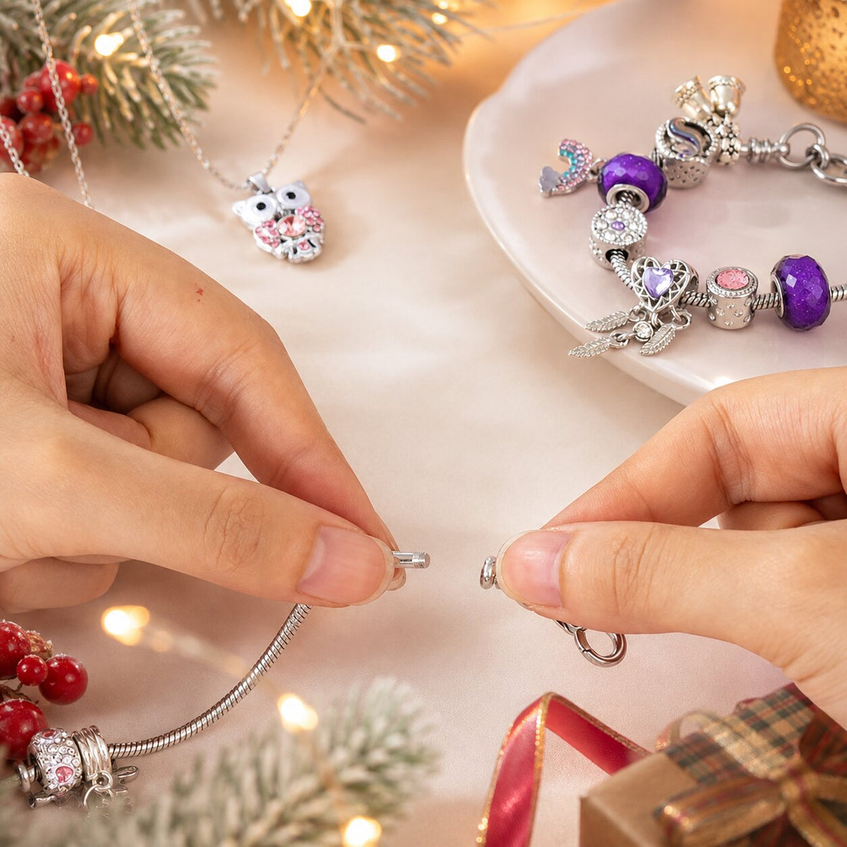 Mains assemblant une breloque sur une chaîne de bracelet, collier hibou à côté