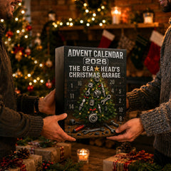 Boîte du calendrier de l'Avent 2026 tenue à deux mains devant un sapin illuminé