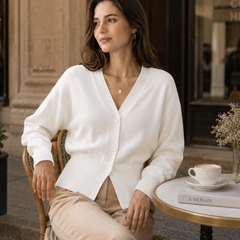 Femme assise en terrasse portant un cardigan blanc court à poignets côtelés