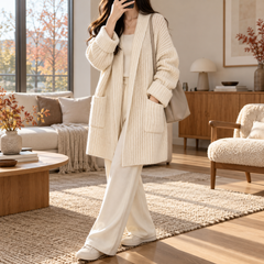 Cardigan blanc ouvert sur un top clair et un pantalon large