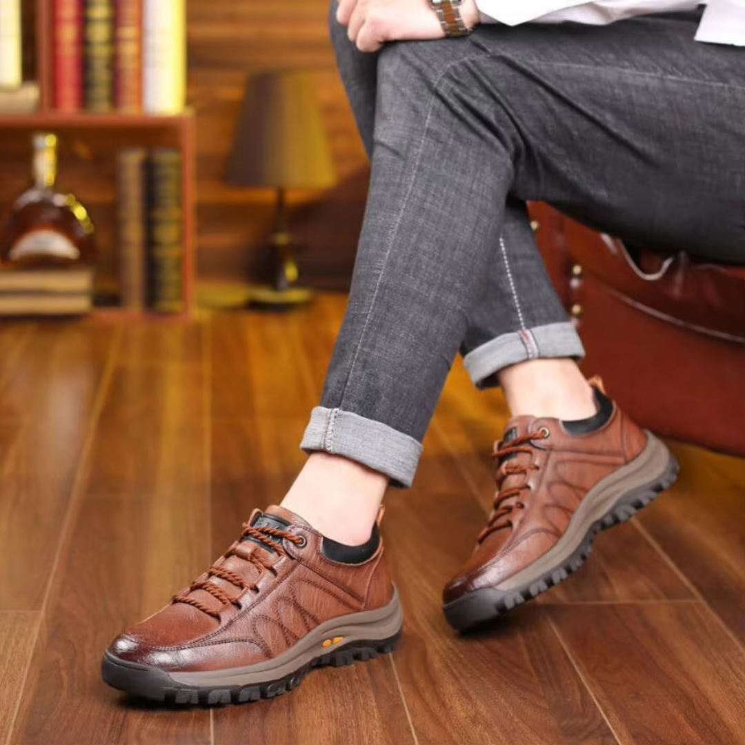Chaussures de marche homme marron portées avec un pantalon gris, semelle crantée visible