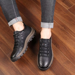 Chaussures de marche homme noires à lacets portées avec un pantalon gris retroussé