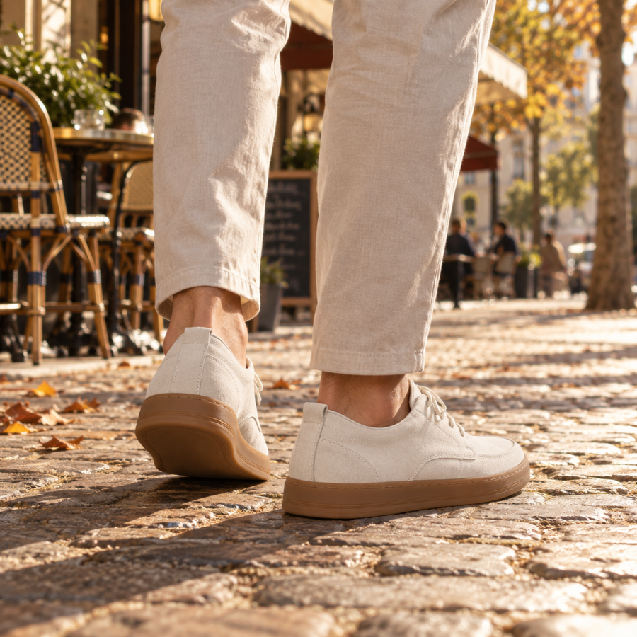 Chaussures blanches vues de dos, talon plat et semelle gomme épaisse sur pavés