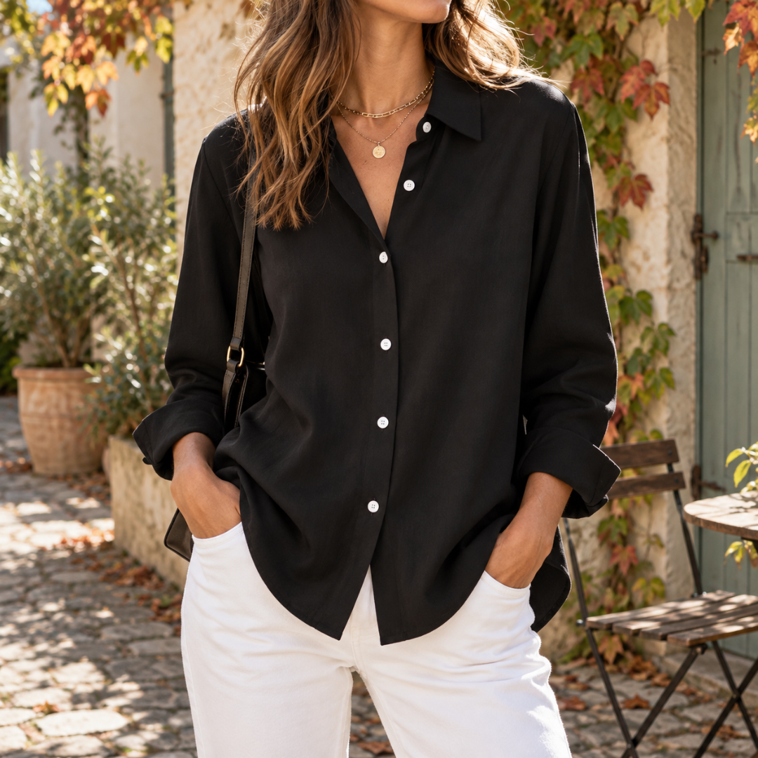Chemise femme noire à col pointu et boutons clairs, portée avec pantalon blanc