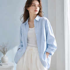 Chemise femme oversize bleu clair boutonnée partiellement sur un pantalon écru