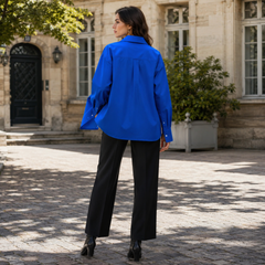 Dos de la chemise bleue oversize avec pli central et bas arrondi allongé