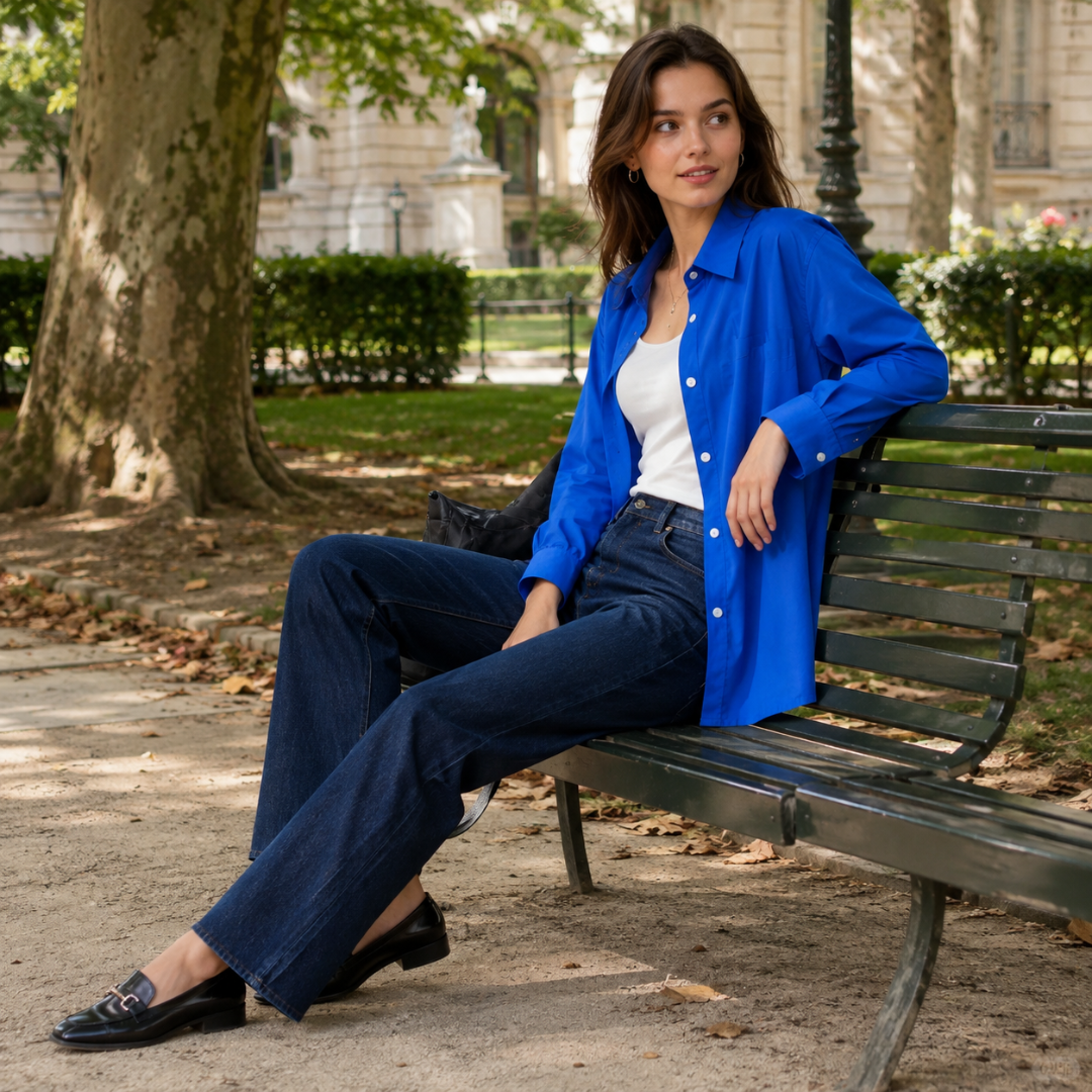 Chemise bleue à poignets boutonnés portée assise sur un banc, avec pantalon foncé