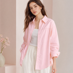 Chemise femme oversize rose pâle portée ouverte sur un pantalon fluide clair