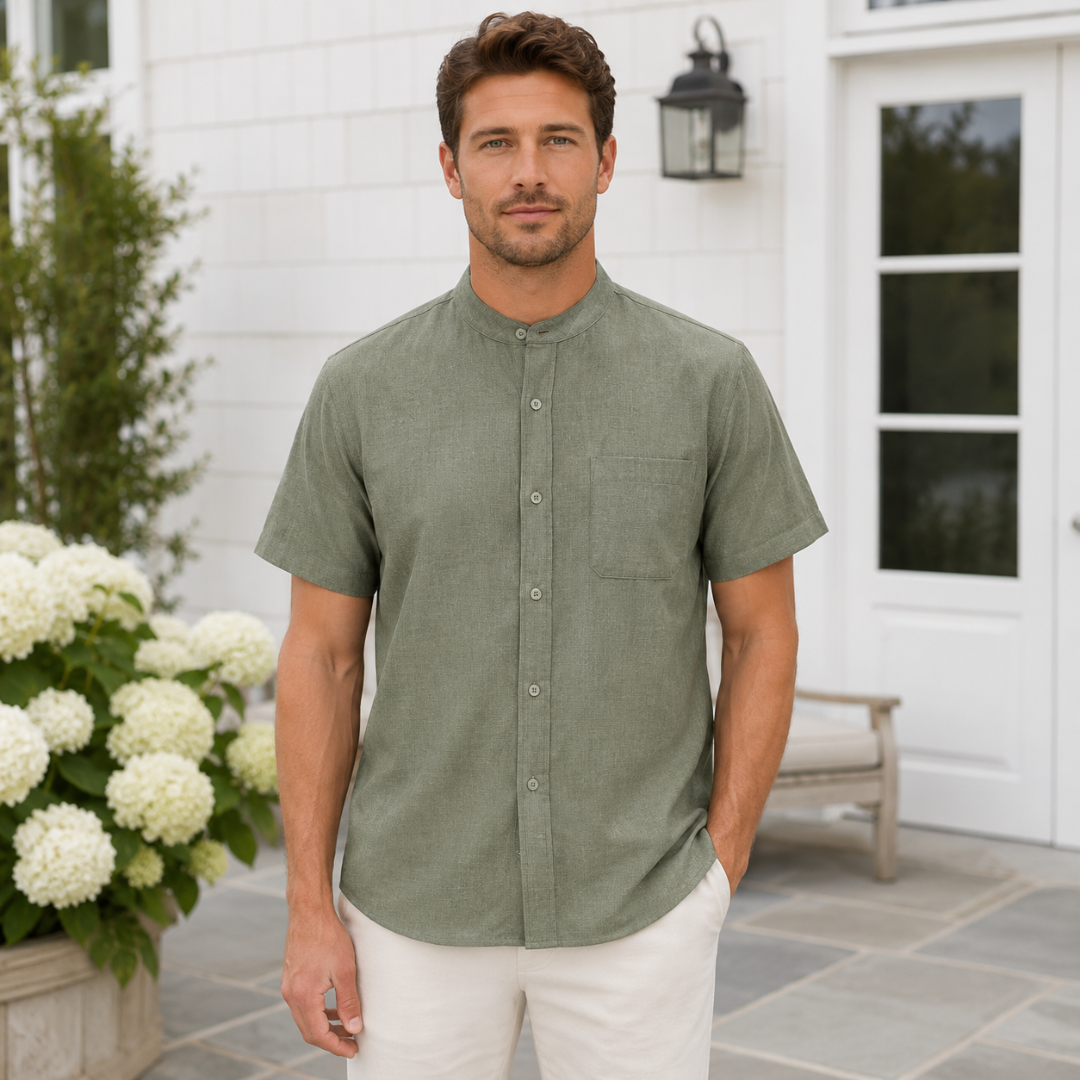 Homme portant une chemise vert olive boutonnée, debout près d'une entrée fleurie