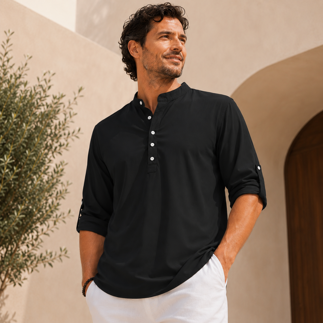 Homme portant une chemise noire col mao, main dans la poche, devant une arche extérieure