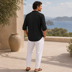 Homme en chemise noire et pantalon blanc se promenant sur un chemin extérieur