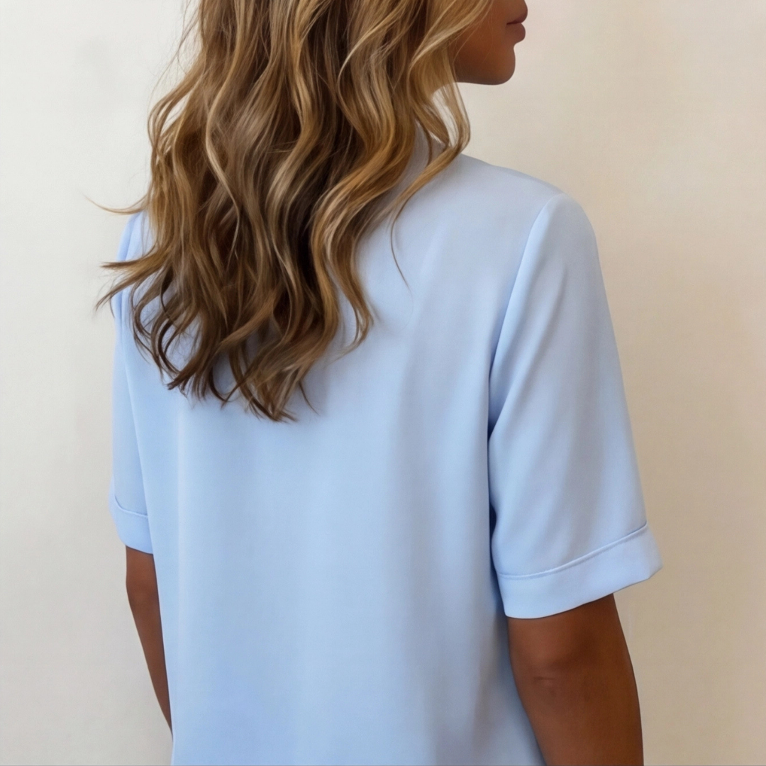 Chemisier bleu clair col V sur fond neutre, détail encolure