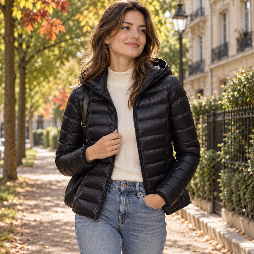 Doudoune femme noire à capuche et matelassage horizontal, portée sur un pull clair