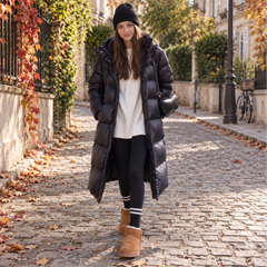 Doudoune longue noire portée sur un pull écru et un legging noir