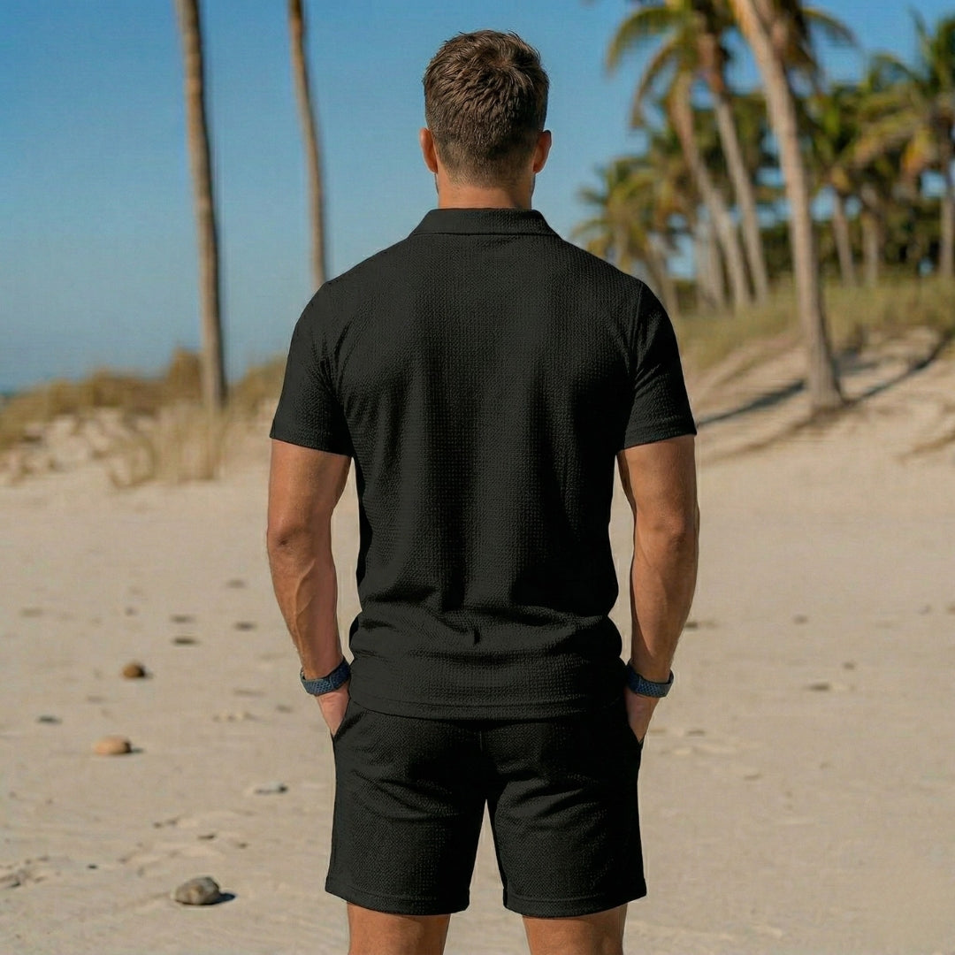 Ensemble homme polo et short noir vue de dos sur le sable