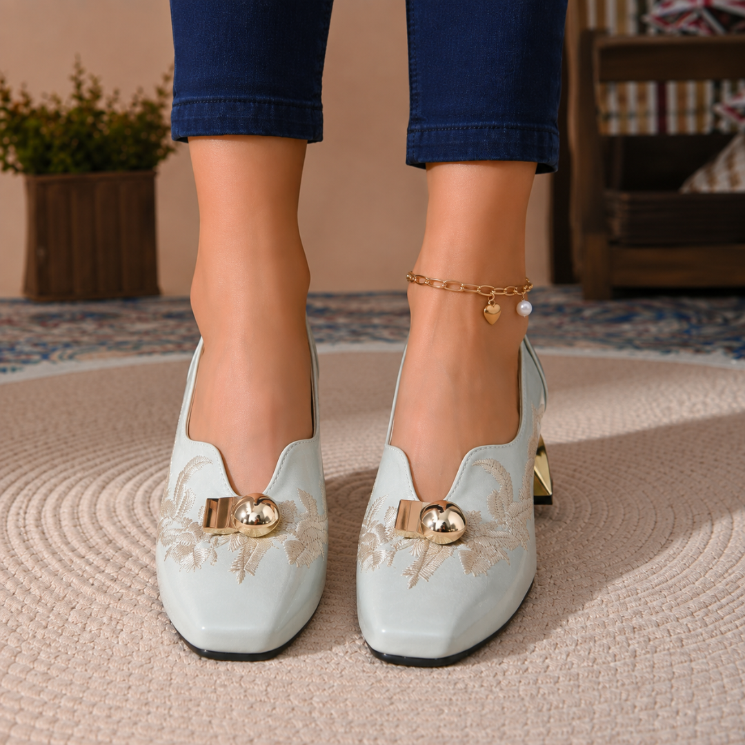 Paire d'escarpins bleus vue de face, broderie claire et boules dorées sur l'empeigne