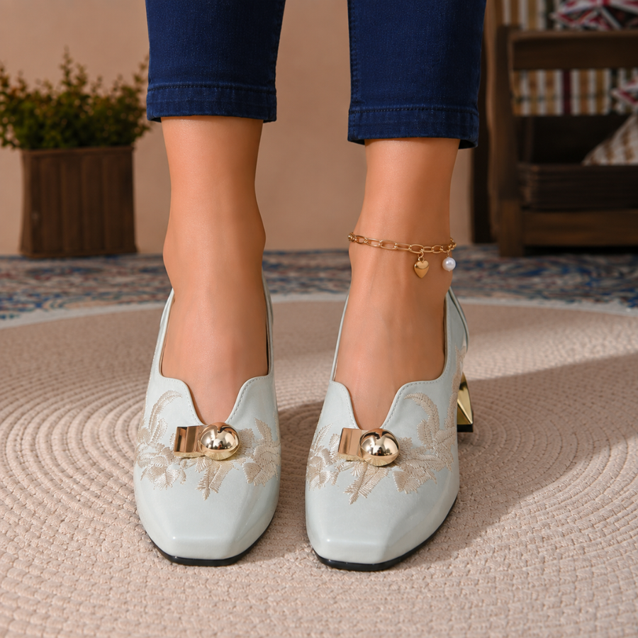 Paire d'escarpins bleus vue de face, broderie claire et boules dorées sur l'empeigne