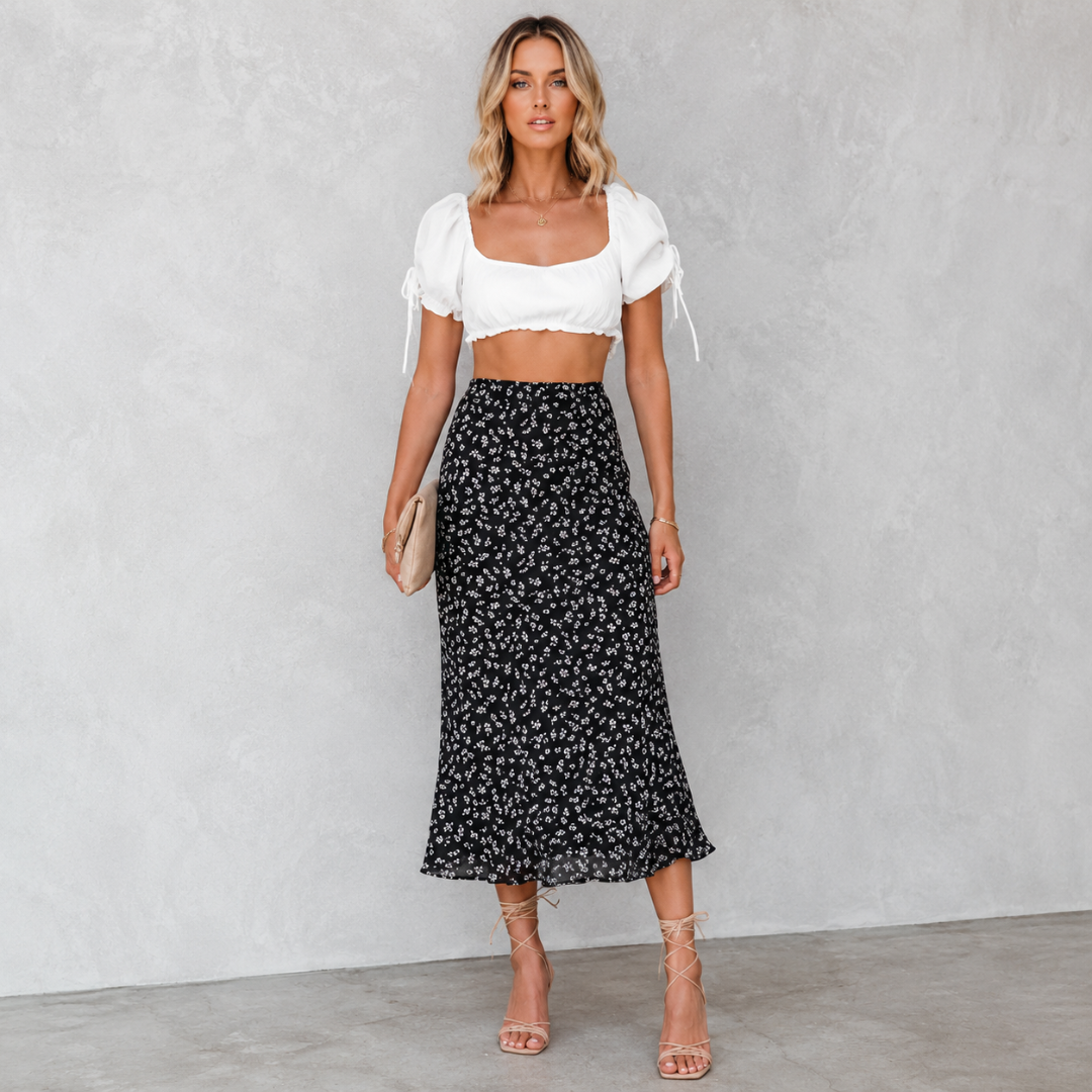 Jupe midi femme noire à imprimé fleuri blanc portée avec top court blanc