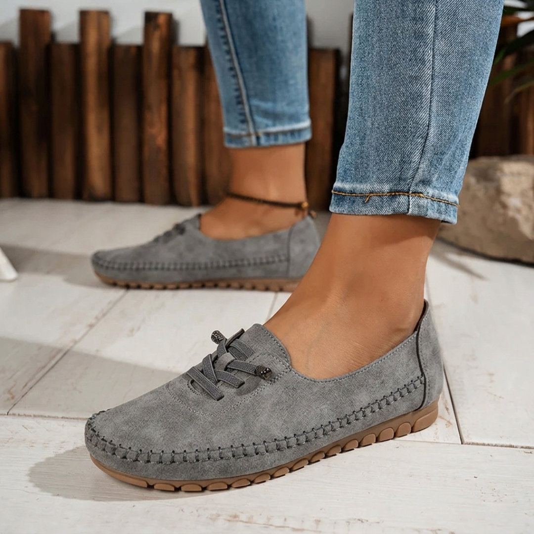 Paire de loafers gris posée sur sol clair, vue de face