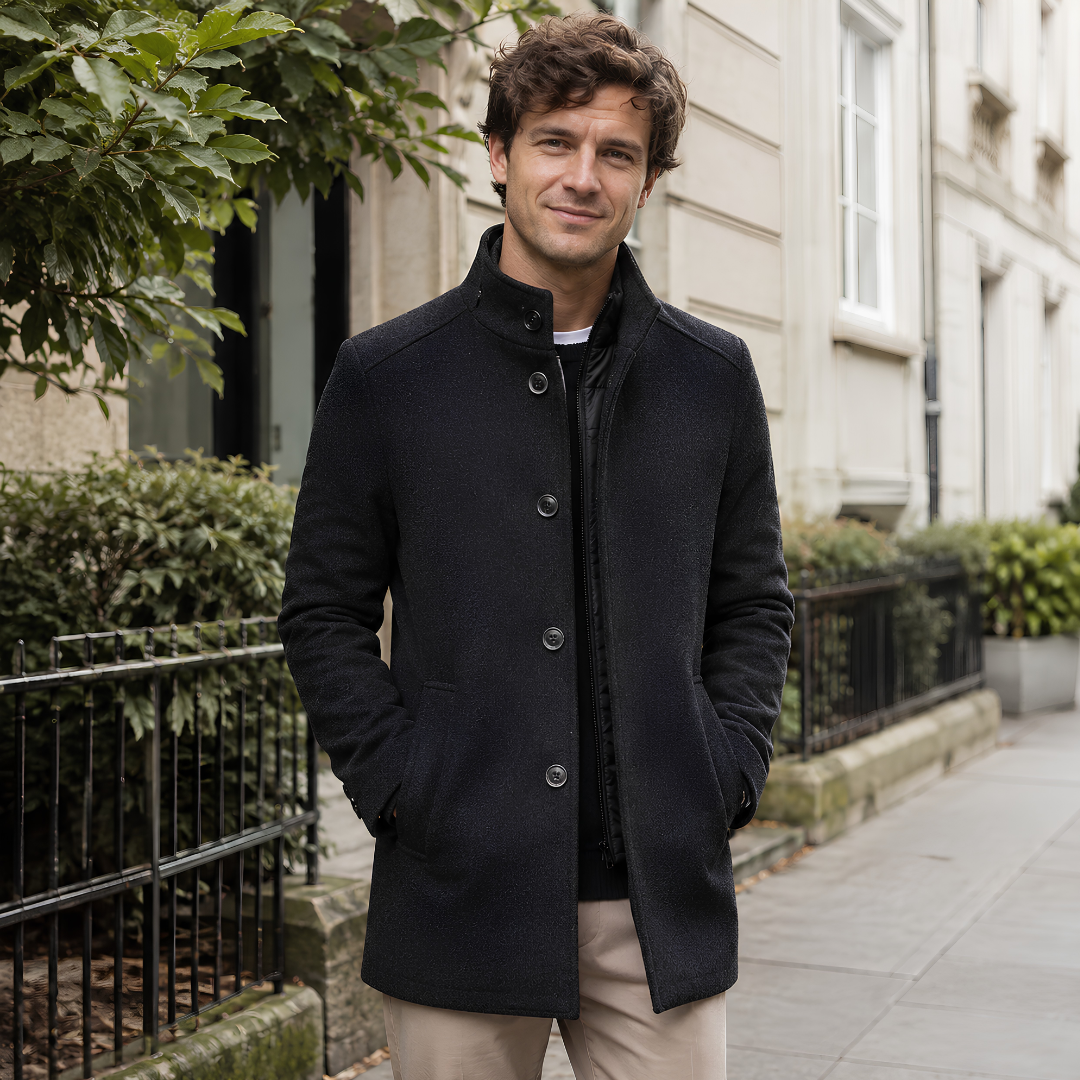 Manteau homme gris foncé à col montant boutonné et poches passepoilées, porté en ville