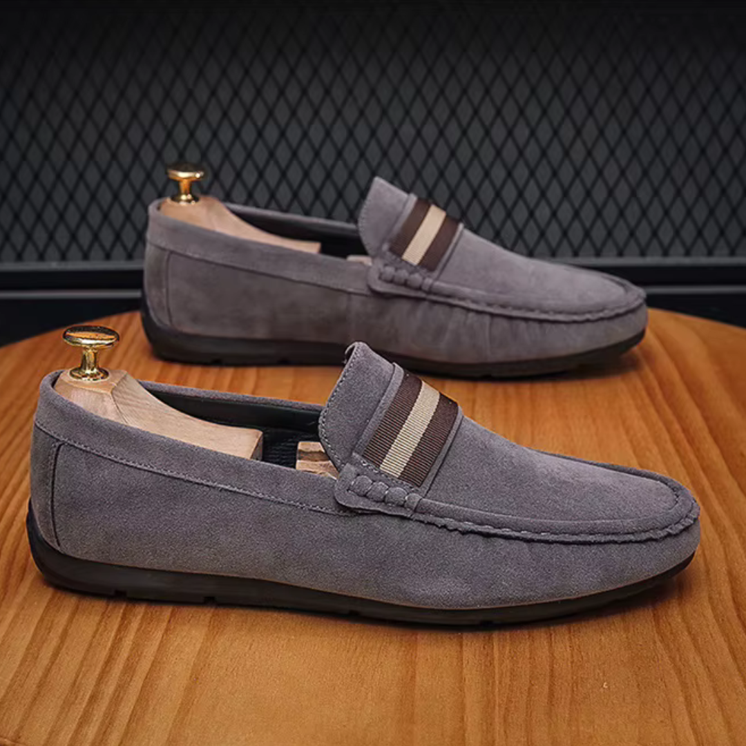 Mocassins gris en daim posés sur une surface neutre