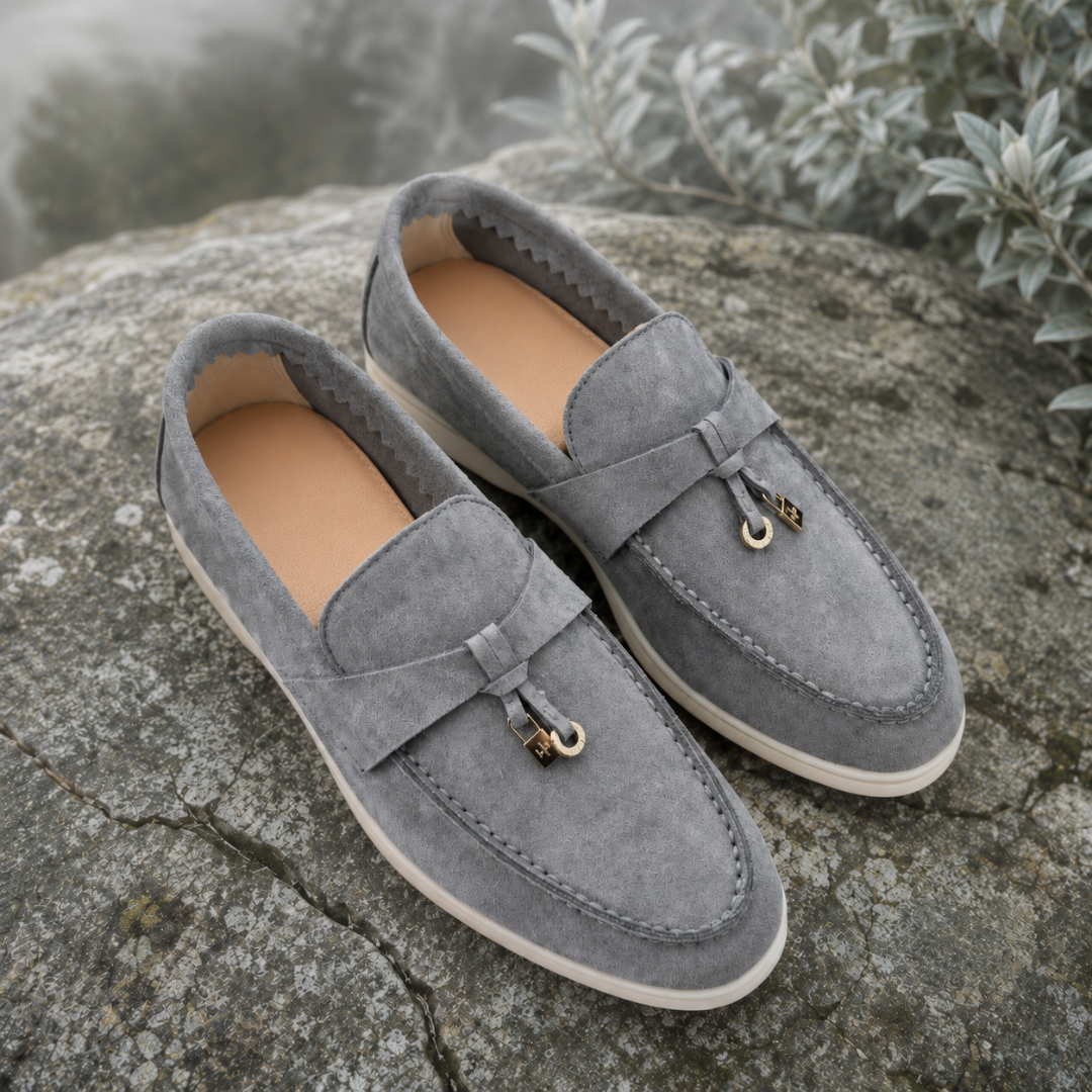 Mocassins femme gris clair posés sur un rocher, breloques dorées et intérieur beige