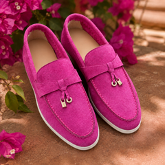 Mocassins femme rose vif devant des bougainvilliers, breloques dorées et semelle blanche