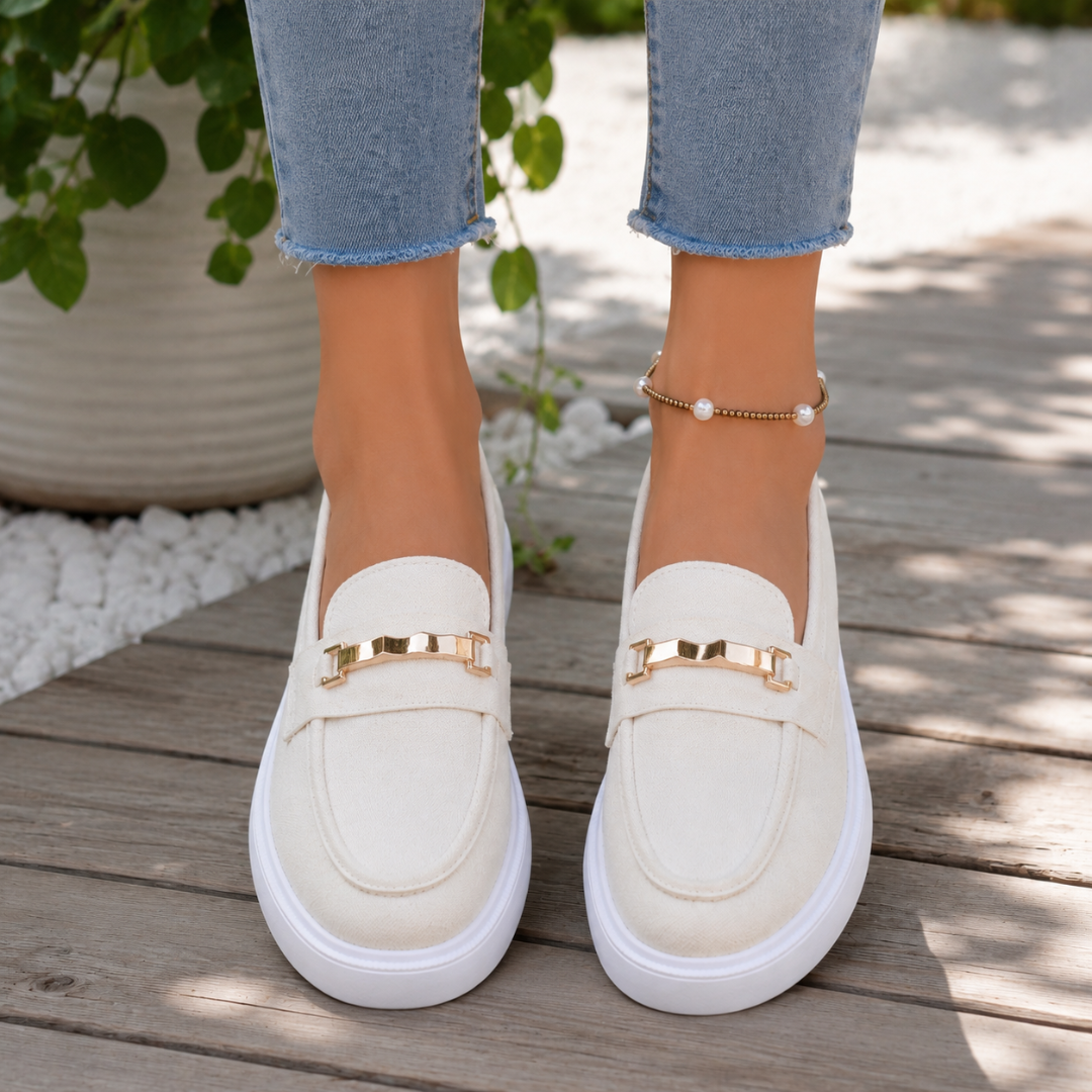 Mocassins femme blancs à chaîne dorée portés avec un pantalon bleu clair, plateforme blanche