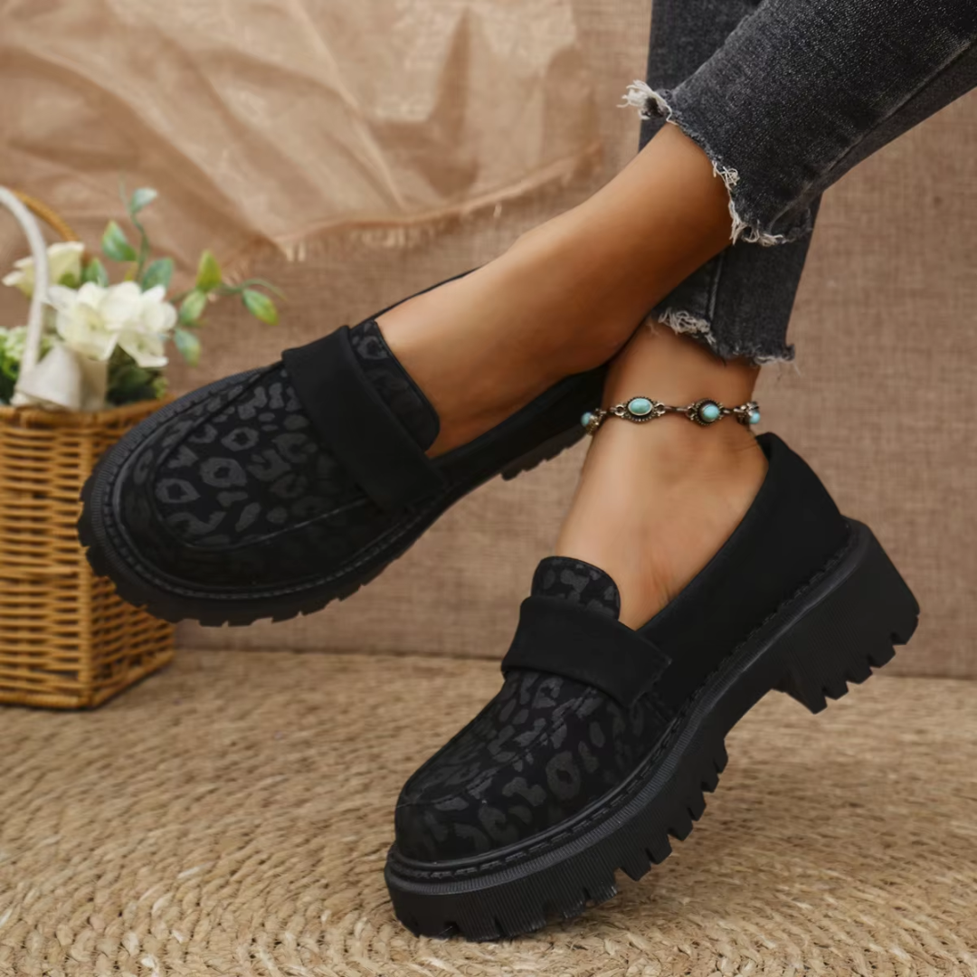 Mocassins noirs léopard portés au pied, bride unie posée sur le dessus du modèle