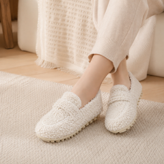 Mocassins femme blancs à l'aspect bouclé portés pieds nus sur un tapis clair