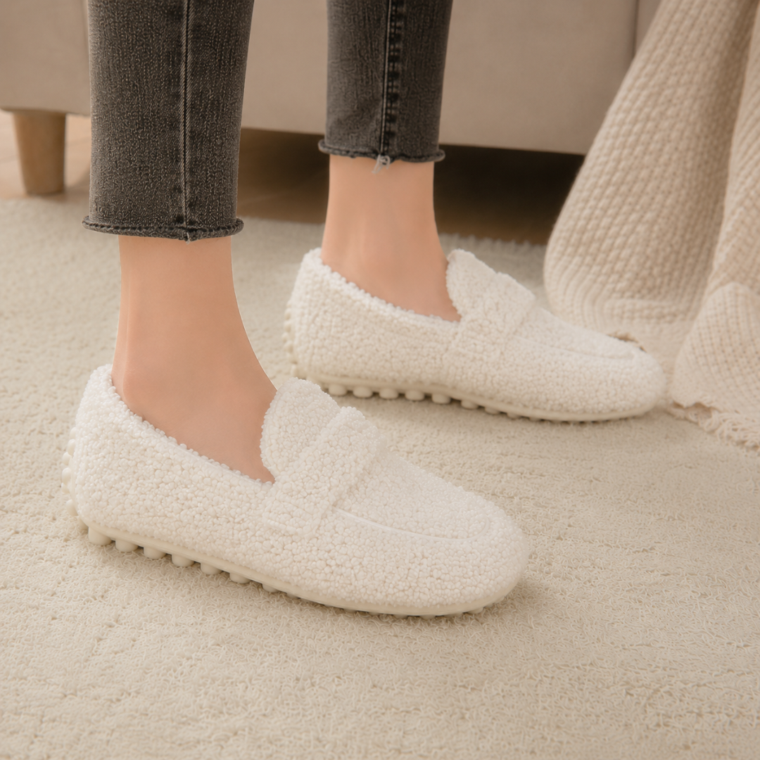 Mocassins blancs effet bouclé portés avec un jean gris sur un tapis crème