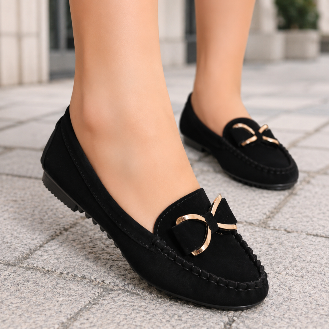 Mocassins noirs plats à nœud métallisé doré portés en ville, semelle crantée visible