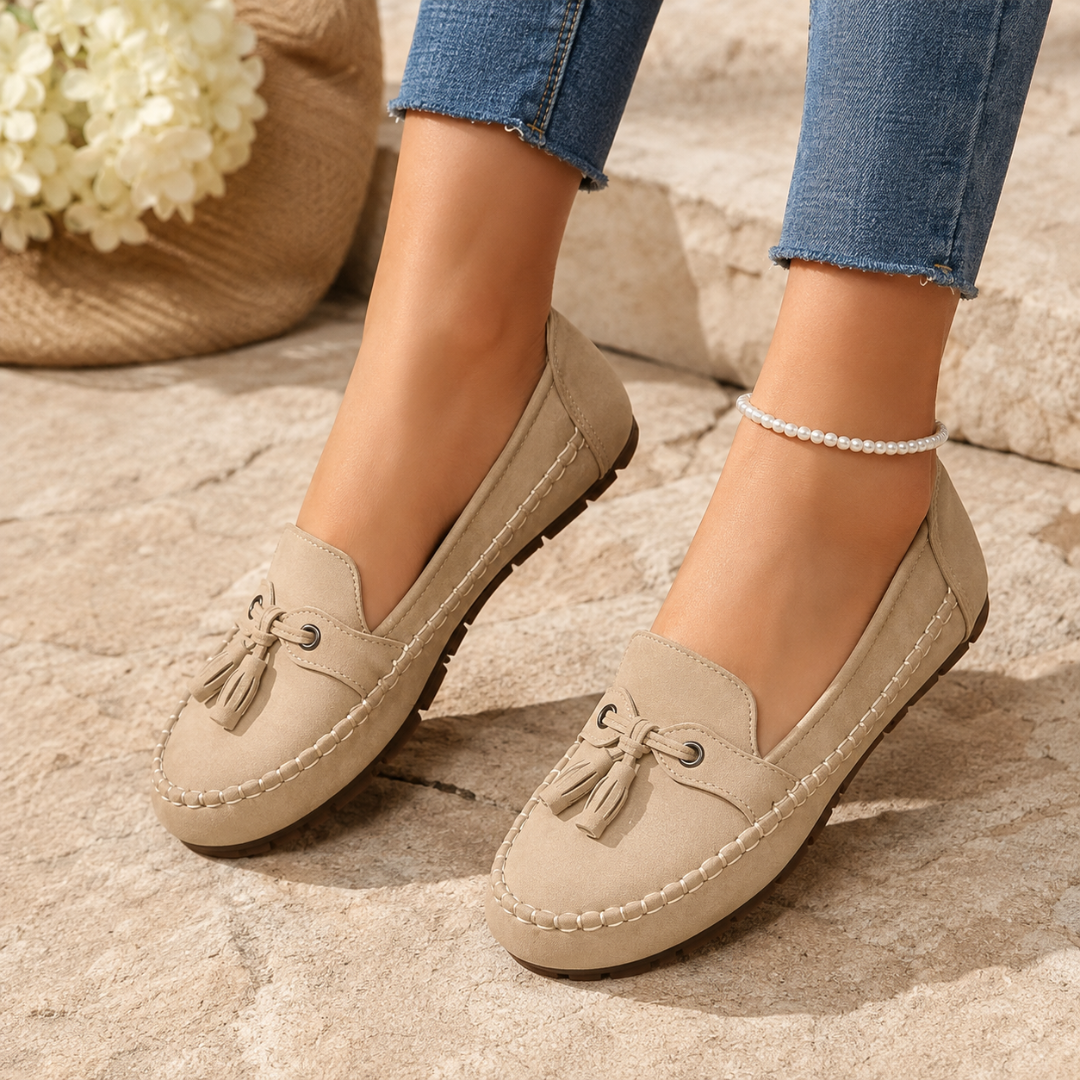 Mocassins femme beige à pompons portés sur la pierre, surpiqûres apparentes ton sur ton