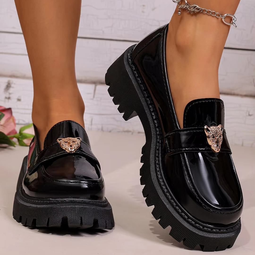 Mocassins noirs brillants portés, bride avec tête de panthère dorée et semelle crantée