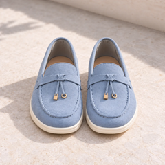 Mocassins homme gris-bleu vus de face, nœud et breloques dorées, semelle blanche