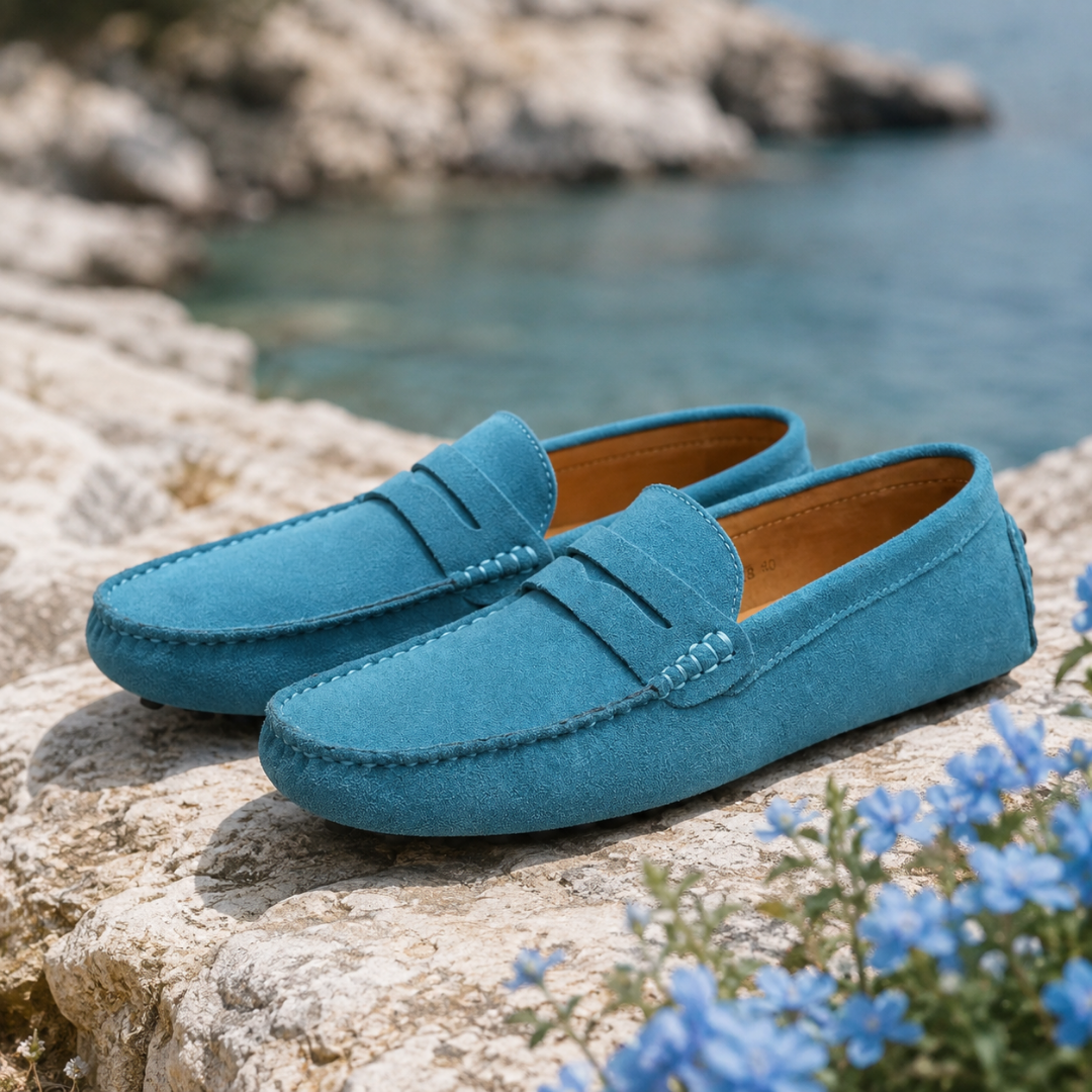 Mocassins homme bleu clair posés sur un rocher, surpiqûres apparentes et bout arrondi