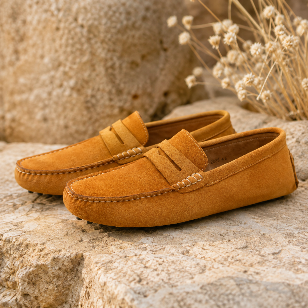 Mocassins homme kaki posés sur une pierre, surpiqûres claires et bout arrondi