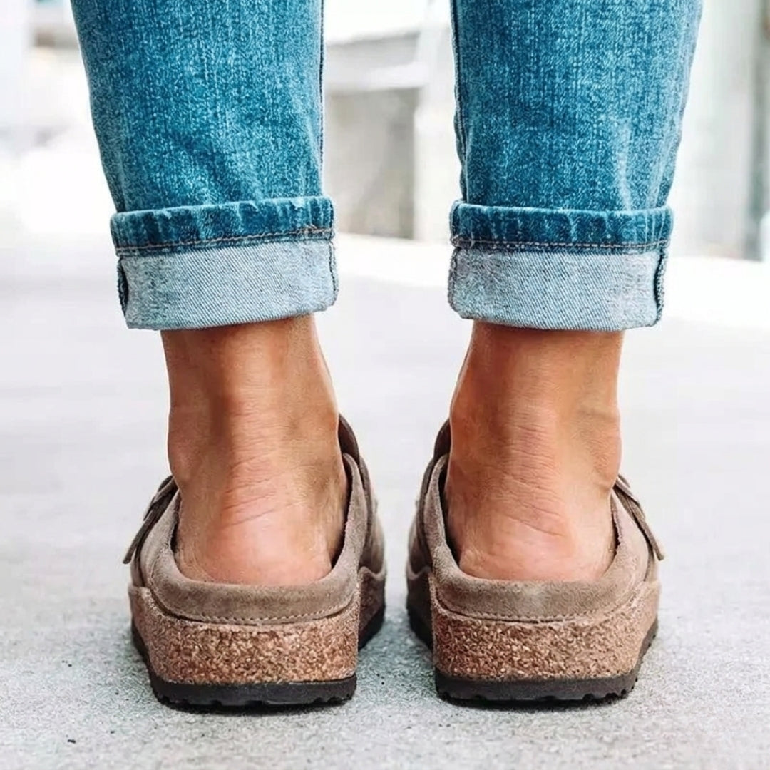 Paire de mules beige suédine posées sur surface claire, vue de trois quarts
