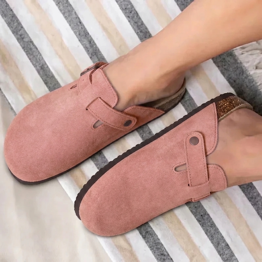 Paire de mules roses posées en angle, boucle dorée visible
