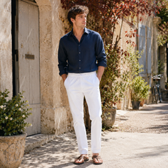 Pantalon homme blanc à cordon, porté avec une chemise bleu marine dans une ruelle