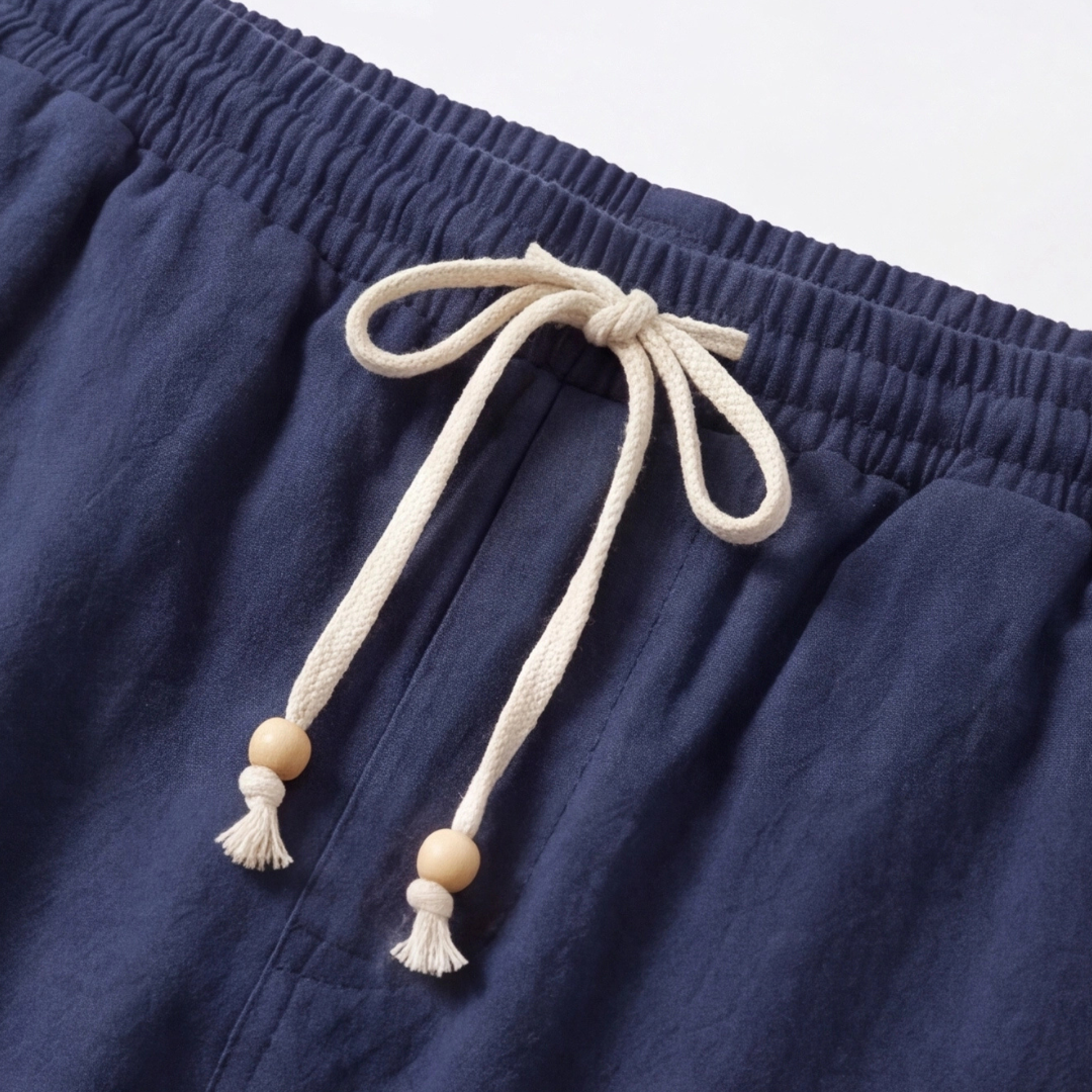 Gros plan sur le cordon de serrage ivoire avec perles en bois du pantalon bleu