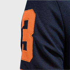 Détail manche polo homme bleu marine avec numéro brodé orange