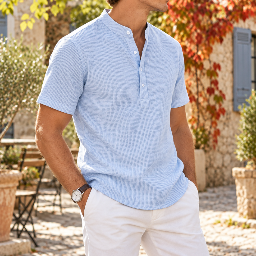 Polo col mao bleu clair porté de trois quarts avec pantalon blanc