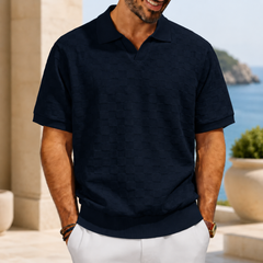 Polo homme bleu marine texturé à col ouvert, décor côtier ensoleillé
