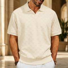 Polo homme crème à maille damier texturée, porté sous une arcade lumineuse